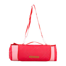 Load image into Gallery viewer, Red and pink picnic mat shown rolled up with strap up and on a white background.